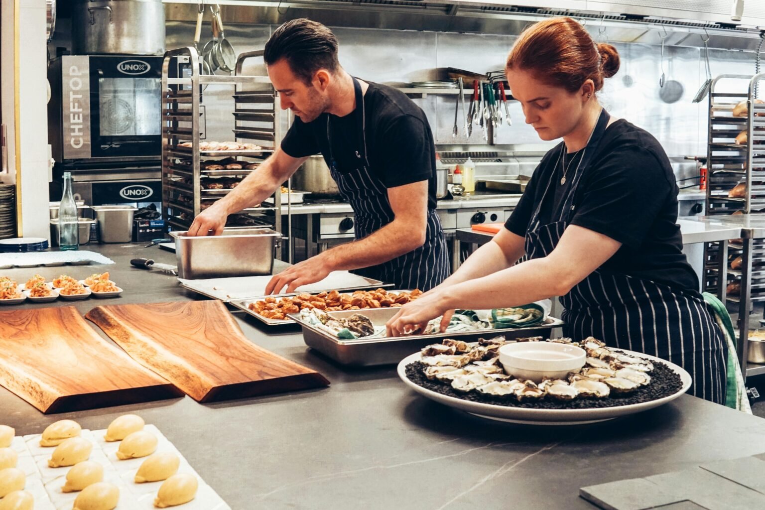 L4 HACCP for Management (CODEX Principles) 1 Two chefs working together in a professional kitchen, preparing gourmet dishes with precision.